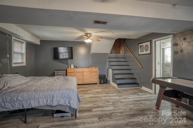 bedroom with a textured ceiling, light hardwood / wood-style floors, ceiling fan, and lofted ceiling