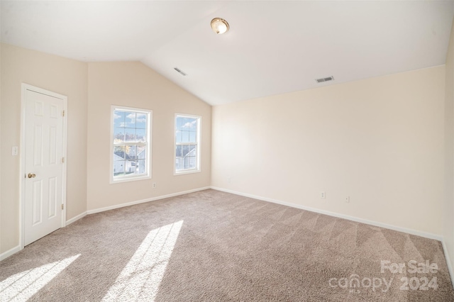 spare room featuring light carpet and lofted ceiling