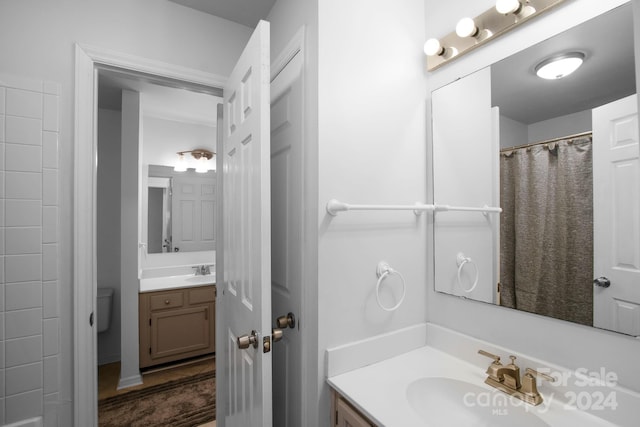 bathroom featuring a shower with shower curtain, vanity, and toilet