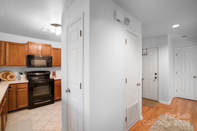 kitchen featuring tasteful backsplash, light hardwood / wood-style flooring, and black appliances