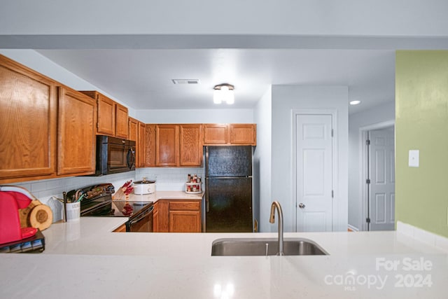 kitchen featuring black appliances, decorative backsplash, kitchen peninsula, and sink