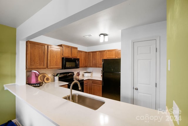 kitchen featuring tasteful backsplash, kitchen peninsula, sink, and black appliances