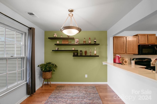 kitchen featuring black appliances, pendant lighting, light wood-type flooring, and tasteful backsplash