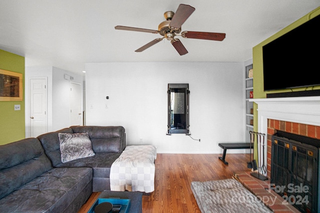 living room with hardwood / wood-style floors, ceiling fan, built in features, and a fireplace