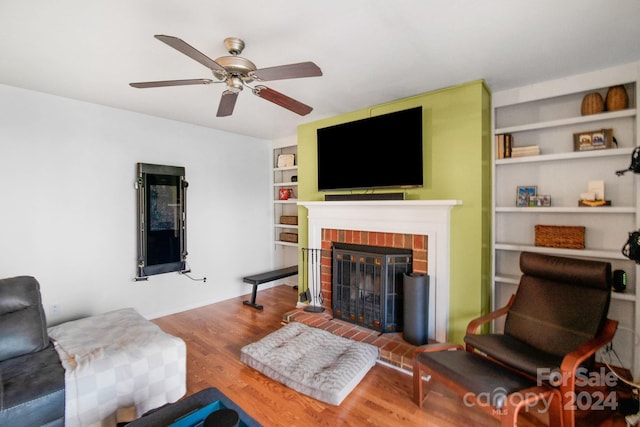 living room with hardwood / wood-style flooring, a brick fireplace, and ceiling fan