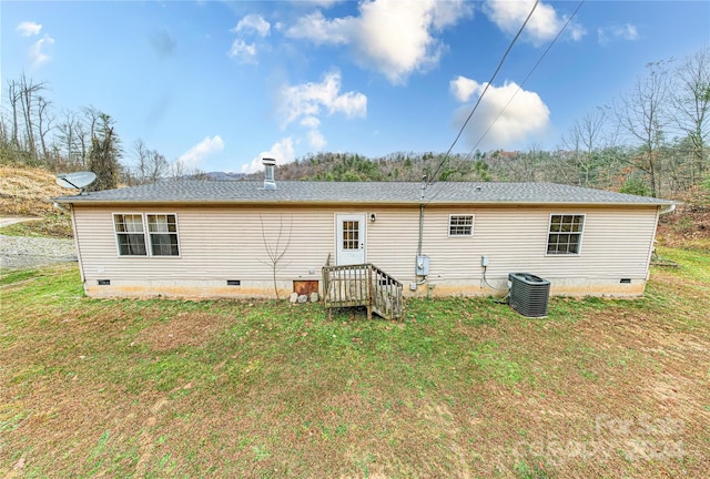 back of property with central air condition unit and a lawn