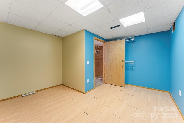 spare room featuring a paneled ceiling and light wood-type flooring