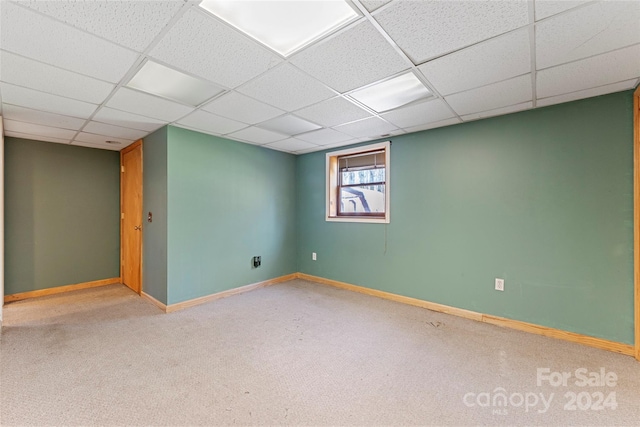 basement with a paneled ceiling and light carpet