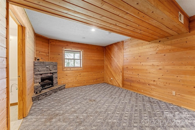 unfurnished living room with wooden walls, a fireplace, and carpet floors