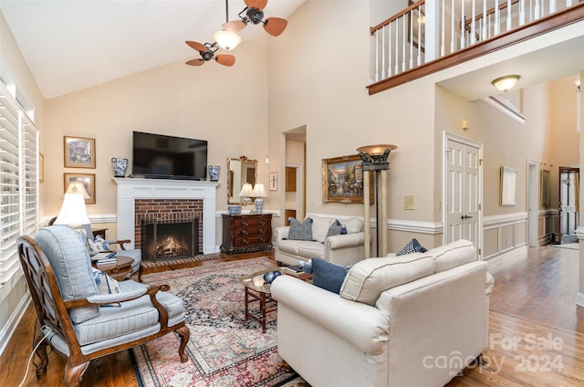 living room featuring ceiling fan, wood-type flooring, a fireplace, and high vaulted ceiling