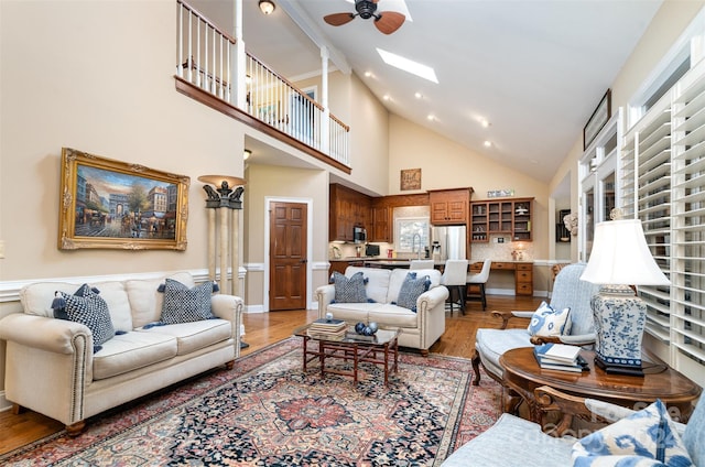 living room with a wealth of natural light, ceiling fan, high vaulted ceiling, and hardwood / wood-style flooring