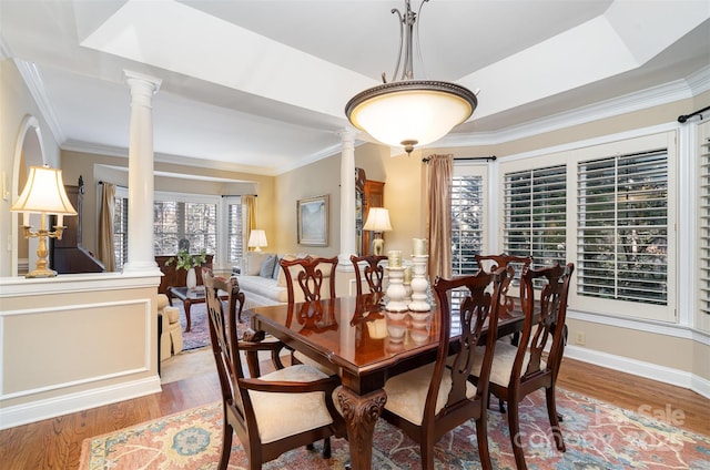 dining space with baseboards, wood finished floors, ornamental molding, and ornate columns