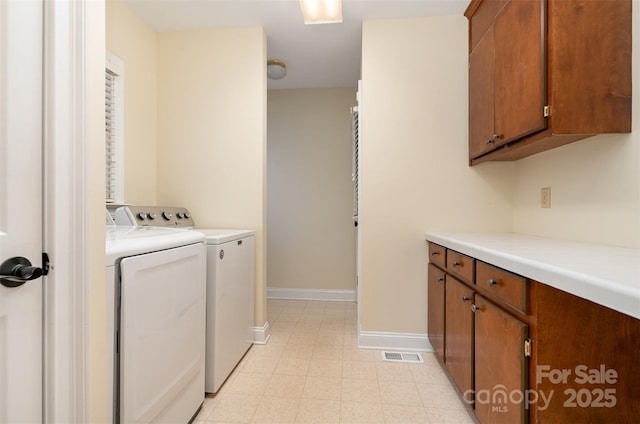laundry room featuring separate washer and dryer, light floors, baseboards, visible vents, and cabinet space