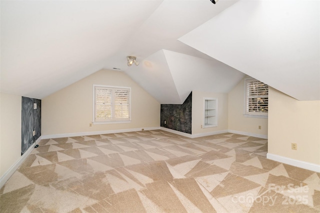 additional living space with lofted ceiling, baseboards, light colored carpet, and built in shelves