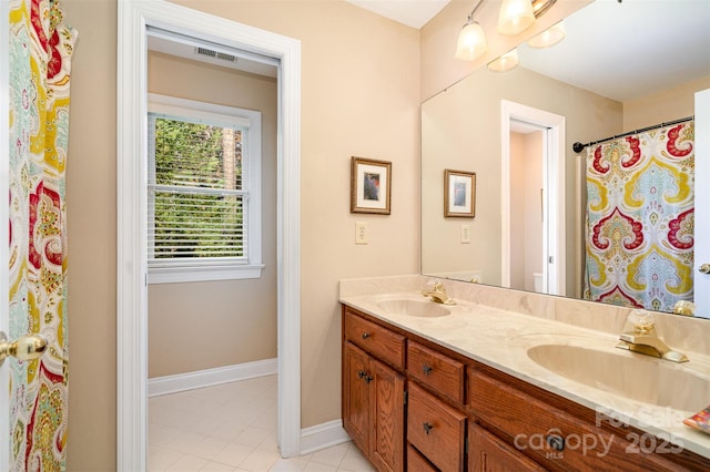 bathroom featuring double vanity, visible vents, baseboards, and a sink
