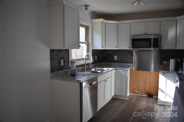 kitchen with white cabinetry, sink, light stone countertops, dark hardwood / wood-style flooring, and appliances with stainless steel finishes