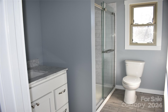 bathroom with vanity, toilet, wood-type flooring, and a shower with door