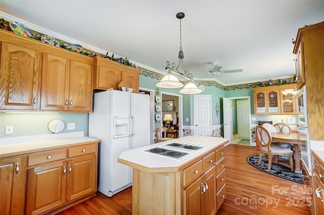 kitchen with decorative light fixtures, white appliances, a kitchen island, crown molding, and light hardwood / wood-style flooring