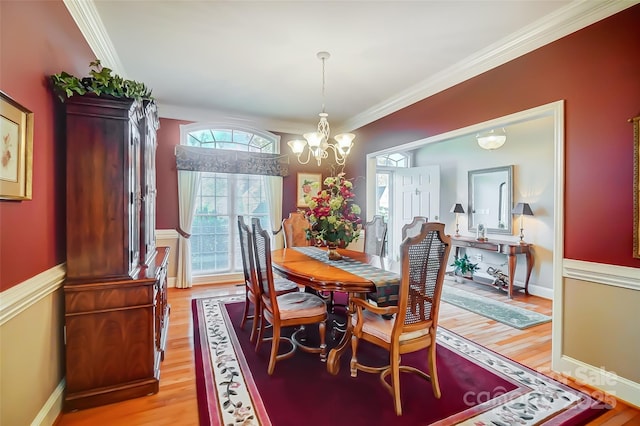 dining room with an inviting chandelier, ornamental molding, and light hardwood / wood-style floors