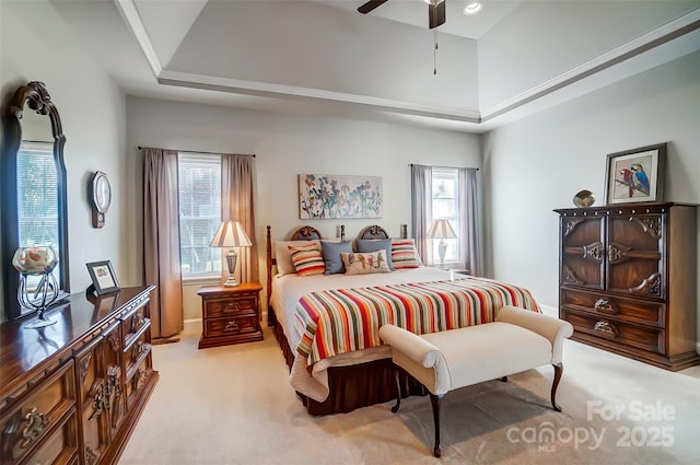 bedroom with ceiling fan, light colored carpet, a high ceiling, and a raised ceiling