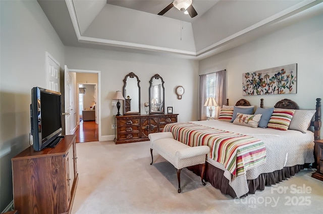 carpeted bedroom featuring ceiling fan and a raised ceiling