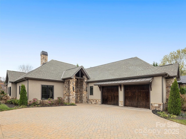 9 Haverhill Way, Arden, NC 28704 - view of front facade featuring stone siding, a garage, a chimney, decorative driveway, and stucco siding