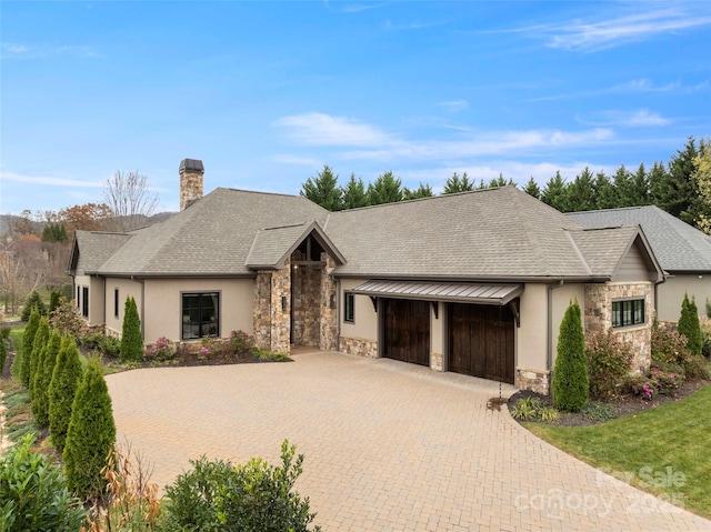 9 Haverhill Way, Arden, NC 28704 - view of front facade featuring stone siding, a garage, a chimney, stucco siding, and a shingled roof