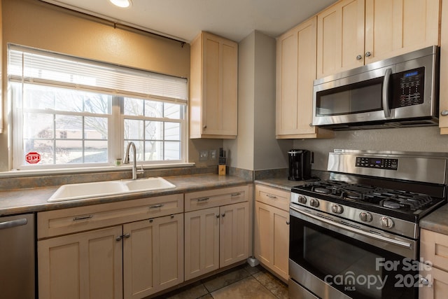 kitchen featuring cream cabinetry, sink, dark tile patterned floors, and stainless steel appliances