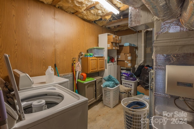 clothes washing area featuring cabinets, washer / dryer, and wooden walls