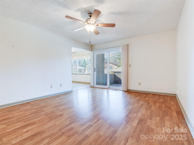 empty room with ceiling fan, a textured ceiling, and light wood-type flooring