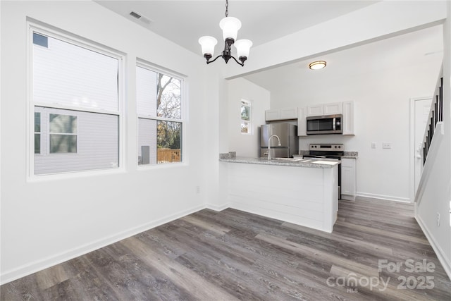 kitchen featuring appliances with stainless steel finishes, white cabinetry, hanging light fixtures, light stone counters, and kitchen peninsula