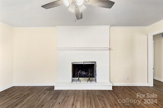 unfurnished living room featuring ceiling fan, dark hardwood / wood-style flooring, crown molding, and a brick fireplace