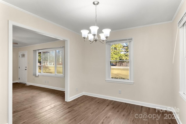 unfurnished dining area with plenty of natural light, dark hardwood / wood-style floors, ornamental molding, and an inviting chandelier