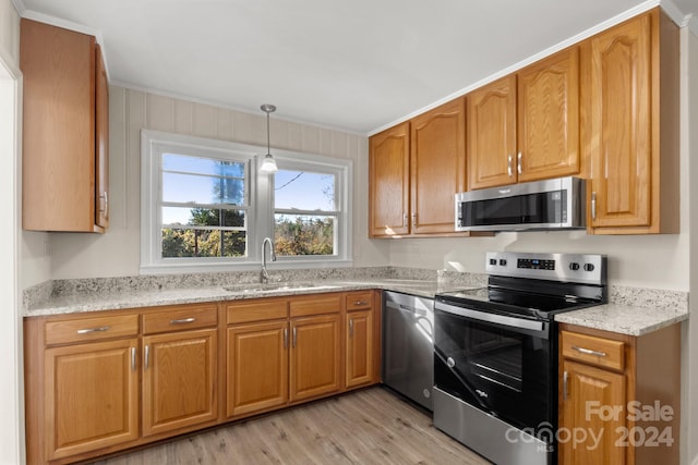 kitchen with light stone countertops, appliances with stainless steel finishes, light wood-type flooring, and sink