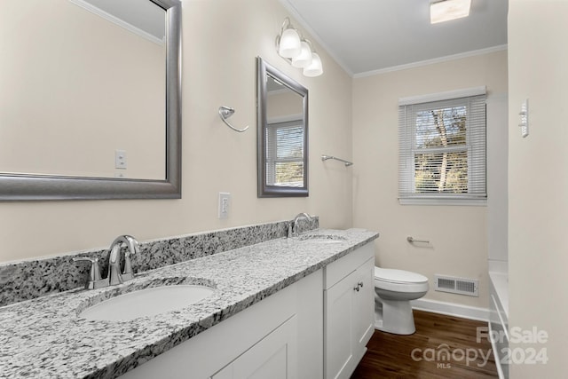 bathroom with ornamental molding, vanity, a bath, hardwood / wood-style floors, and toilet