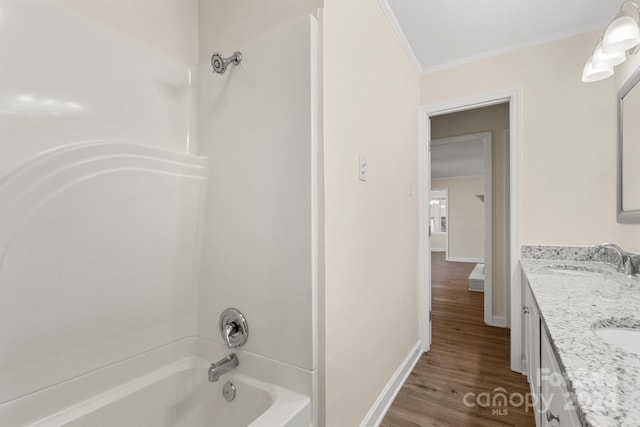 bathroom with hardwood / wood-style flooring, vanity, crown molding, and bathtub / shower combination