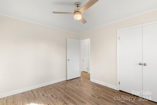 unfurnished bedroom featuring ceiling fan, a closet, crown molding, and light hardwood / wood-style flooring