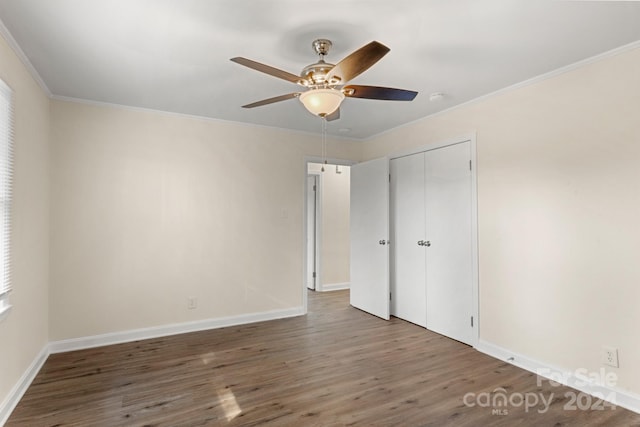 unfurnished bedroom with ceiling fan, a closet, dark hardwood / wood-style floors, and ornamental molding