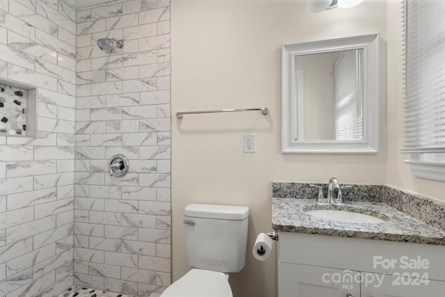 bathroom featuring vanity, toilet, and tiled shower