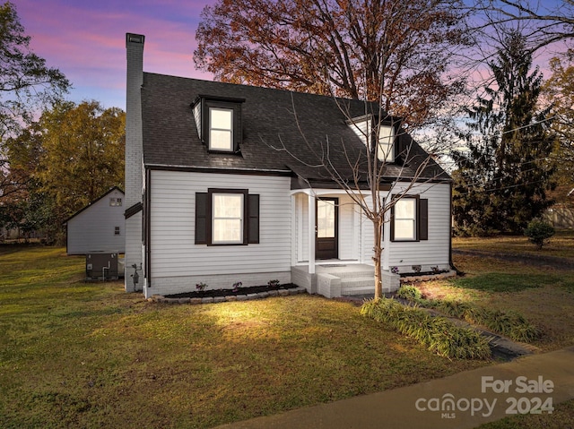 cape cod home featuring a yard