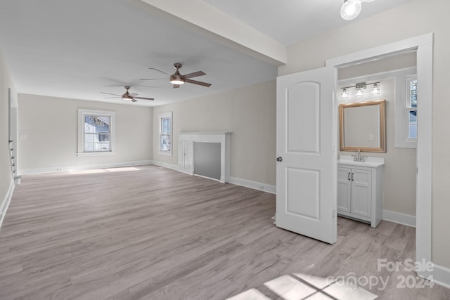 unfurnished living room featuring ceiling fan, light hardwood / wood-style floors, and sink