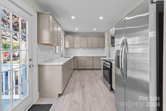 kitchen with decorative backsplash, sink, stainless steel appliances, and light hardwood / wood-style floors