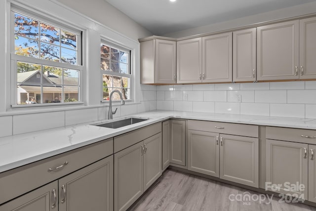 kitchen with gray cabinets, a healthy amount of sunlight, sink, and light hardwood / wood-style flooring