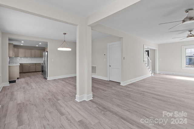 unfurnished living room with ceiling fan, light hardwood / wood-style flooring, and sink