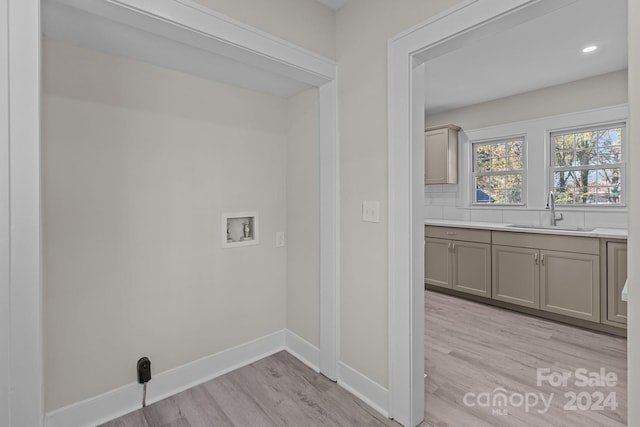 laundry area with sink, hookup for a washing machine, and light hardwood / wood-style flooring