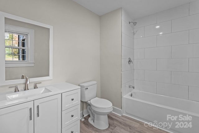 full bathroom featuring hardwood / wood-style floors, vanity, toilet, and tiled shower / bath