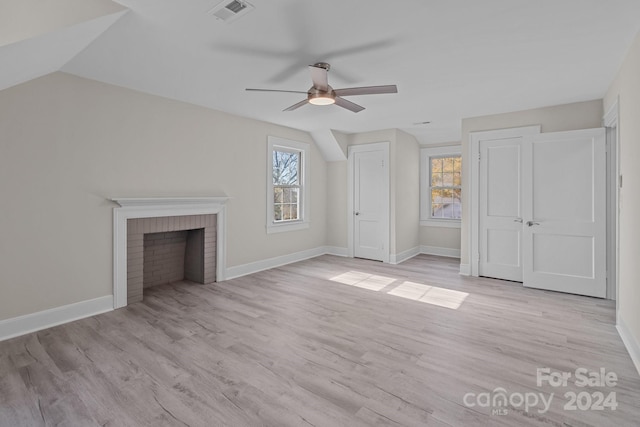 unfurnished living room with light hardwood / wood-style floors, a brick fireplace, and lofted ceiling