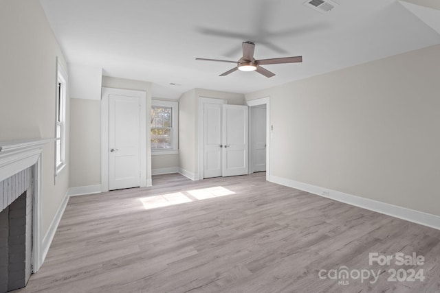 unfurnished bedroom featuring ceiling fan, light hardwood / wood-style floors, and a brick fireplace