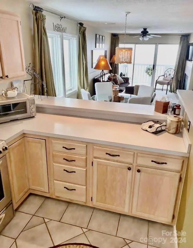 kitchen with ceiling fan, light brown cabinets, light tile patterned floors, pendant lighting, and stainless steel stove