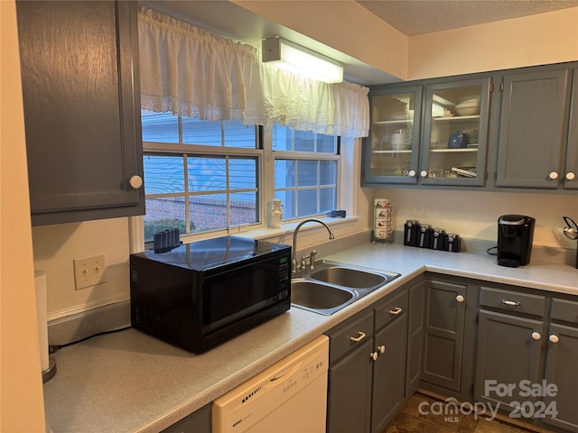 kitchen featuring a textured ceiling, white dishwasher, and sink